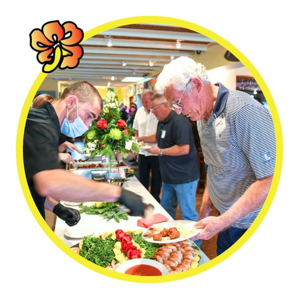 A group of people standing around a table with food.